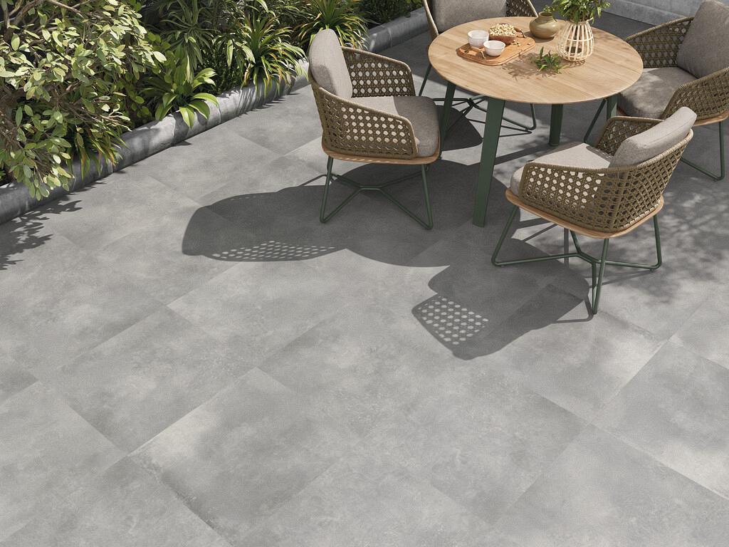 Grijze keramische tegels op groot formaat op een modern terras met tafel en stoelen