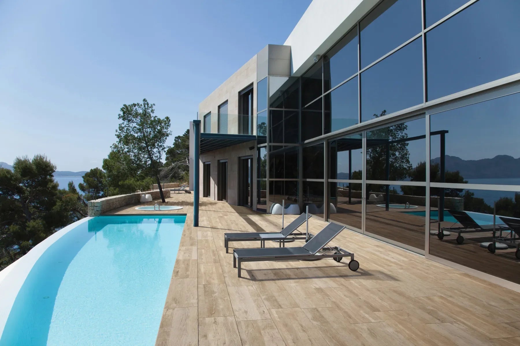 Houtlook keramische tegels rond een zwembad bij een moderne villa
