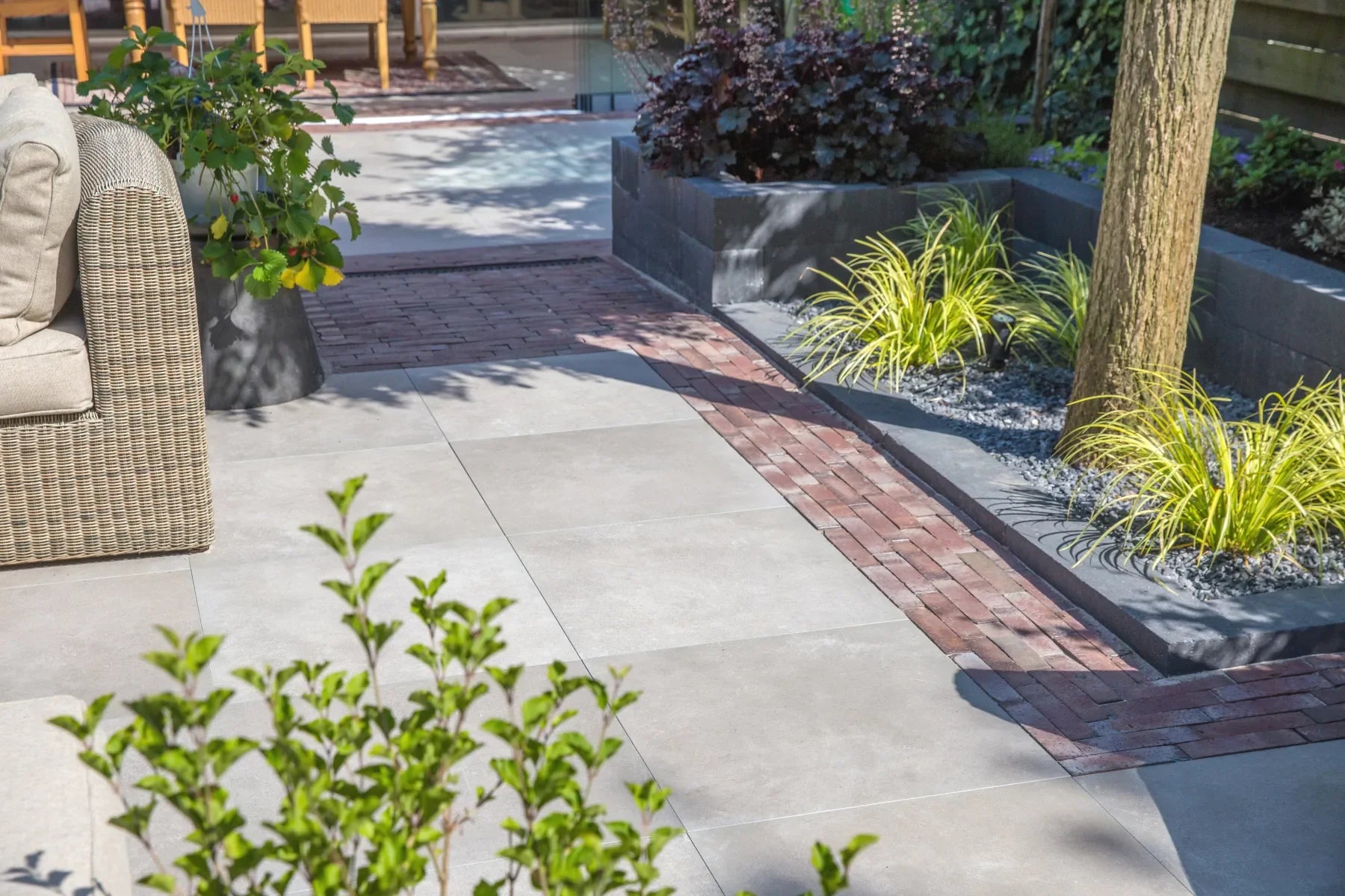 Tuin met keramische bestrating en decoratieve klinkerstroken en kantopsluiting