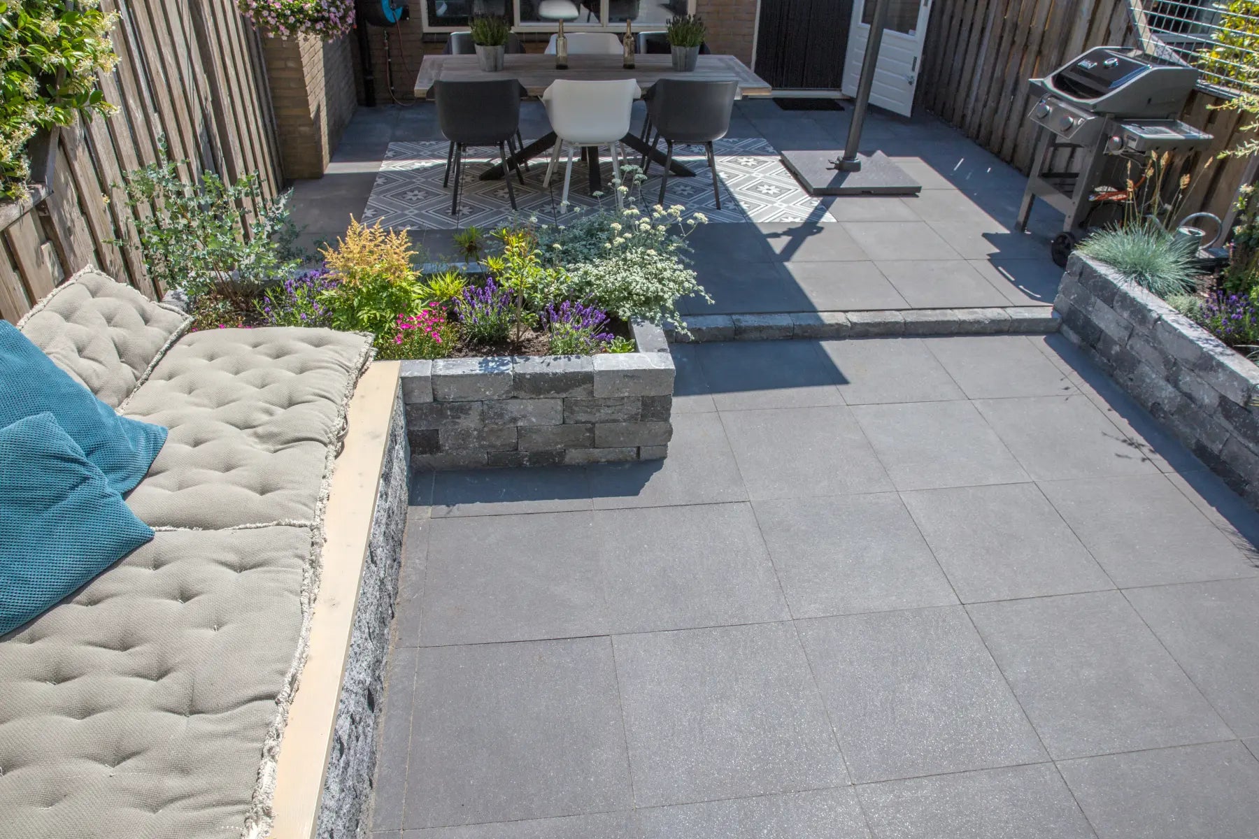 Compact keramisch terras met loungebank, beplanting en eethoek
