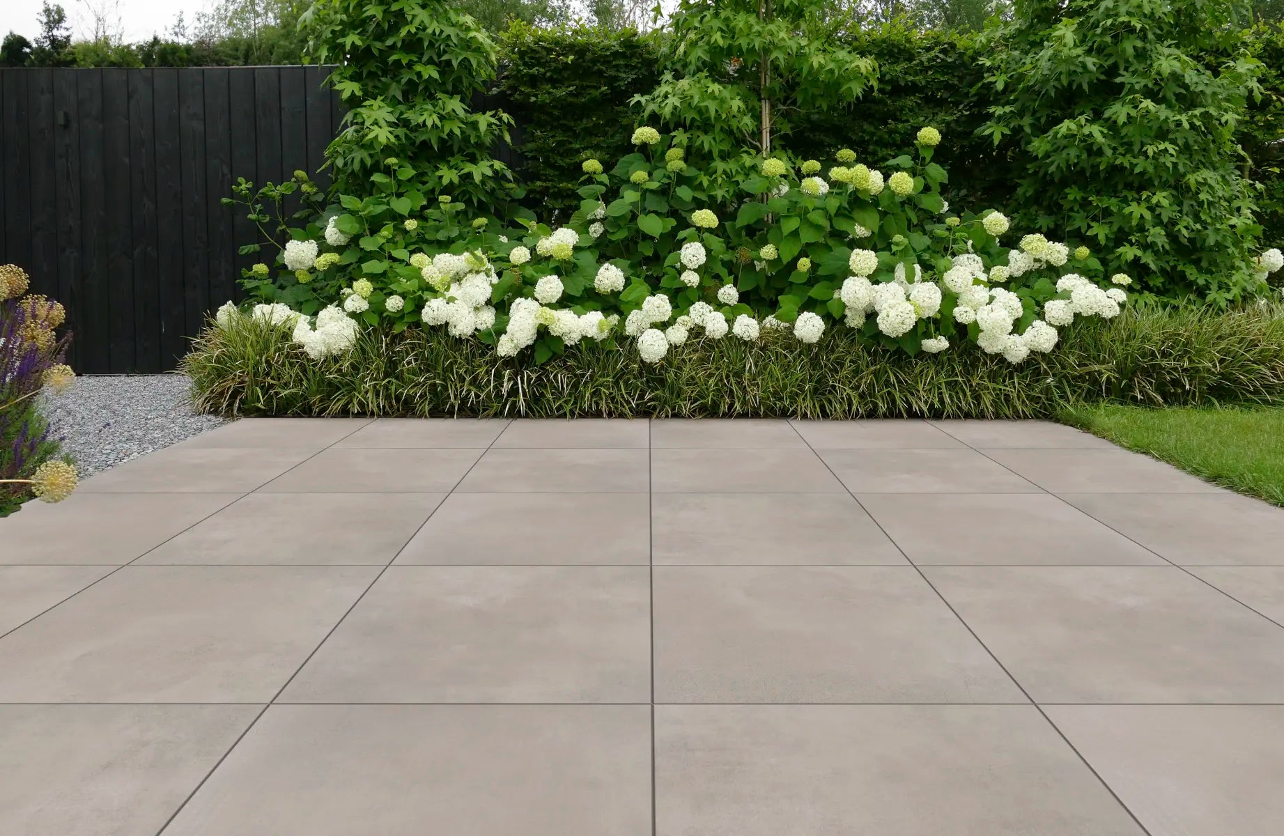 Warm greige keramisch terras met een border vol witte hortensia's
