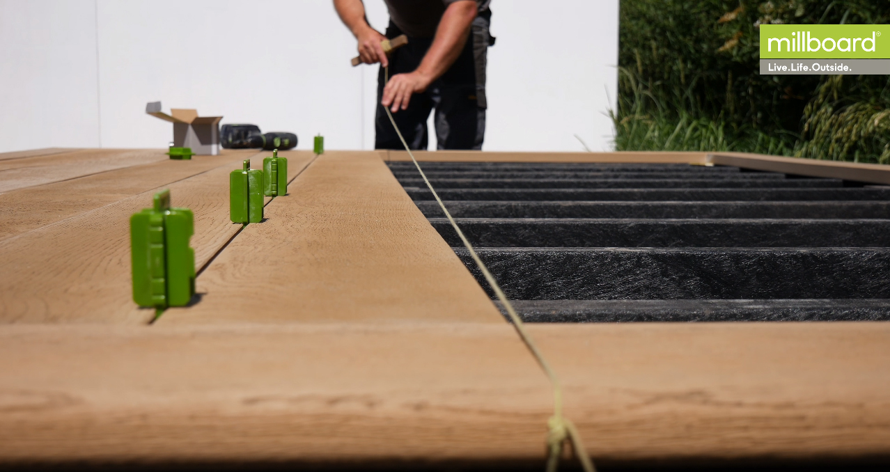 Millboard terras in aanleg met groene afstandhouders tussen de vlonderplanken en een zichtbare onderconstructie
