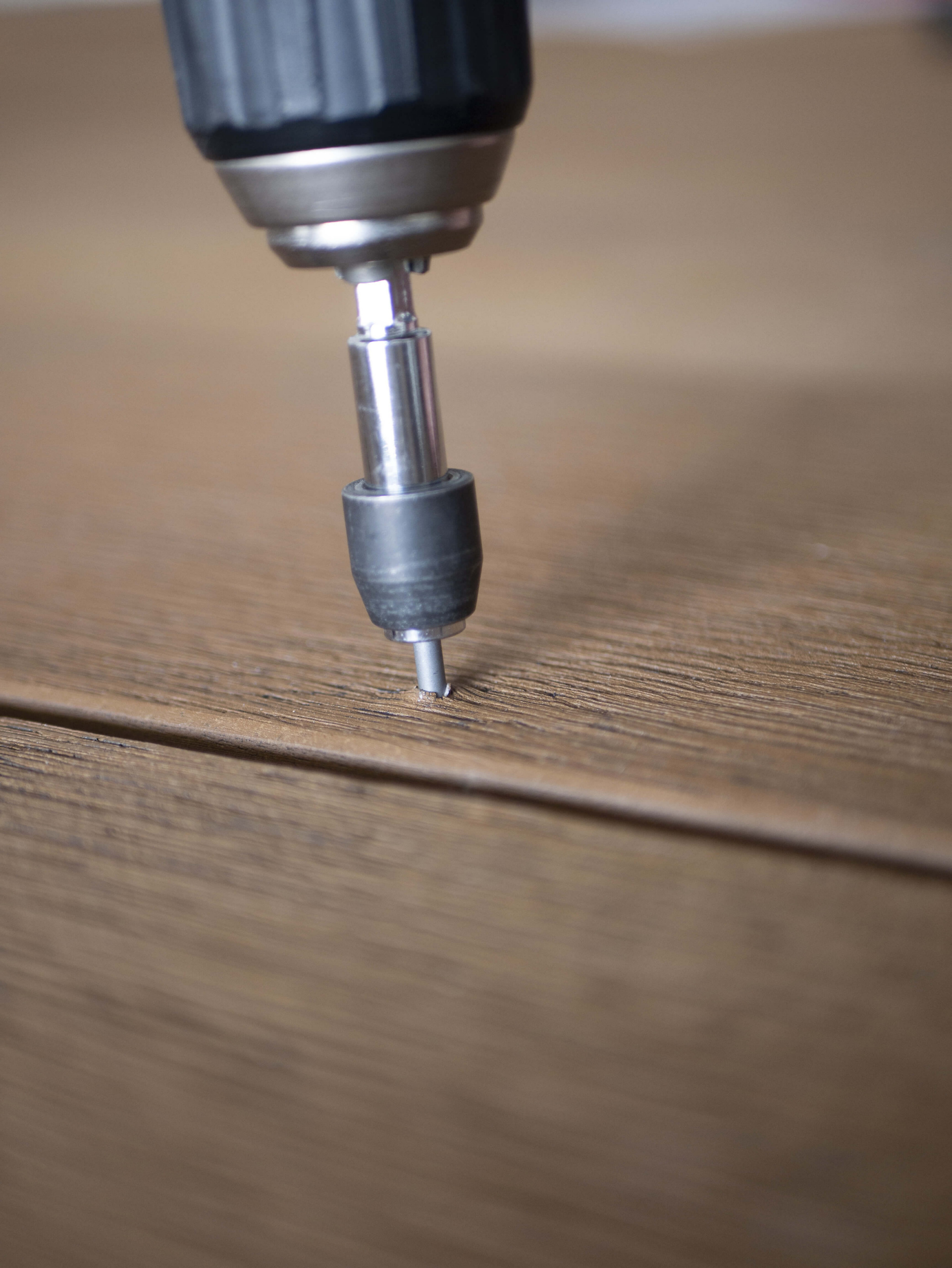 Close-up van het inschroeven van een bevestiging door de houtstructuur van een Millboard vlonderplank